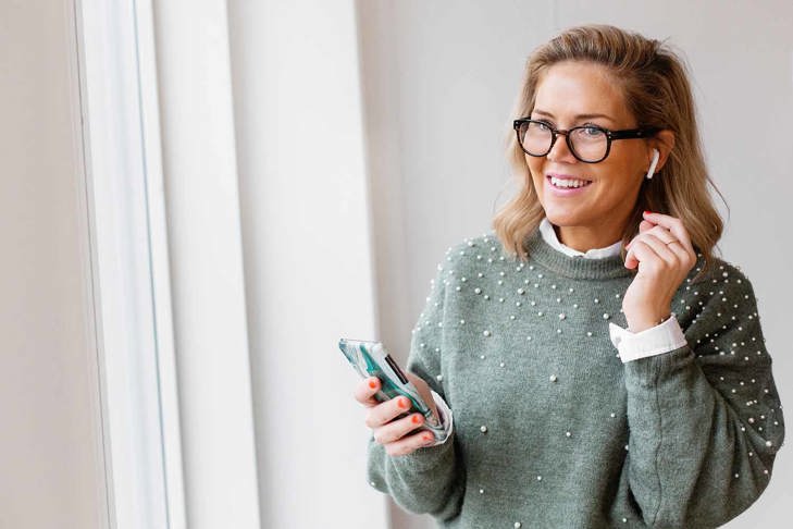 Leende kvinna som håller i en telefon.