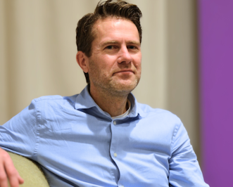 Andres Franzen sitter i en soffa och tittar in i kameran.