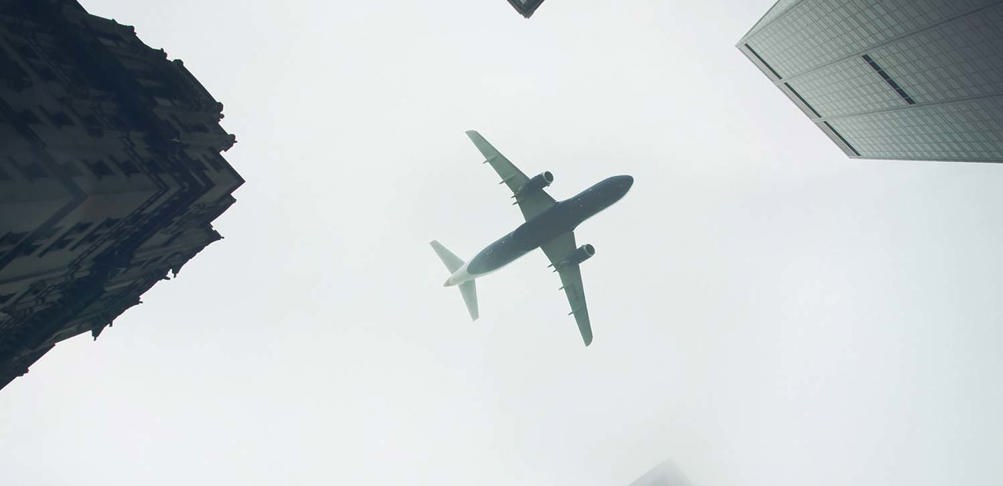 Bild på flygplan som flyger mellan skyskrapor