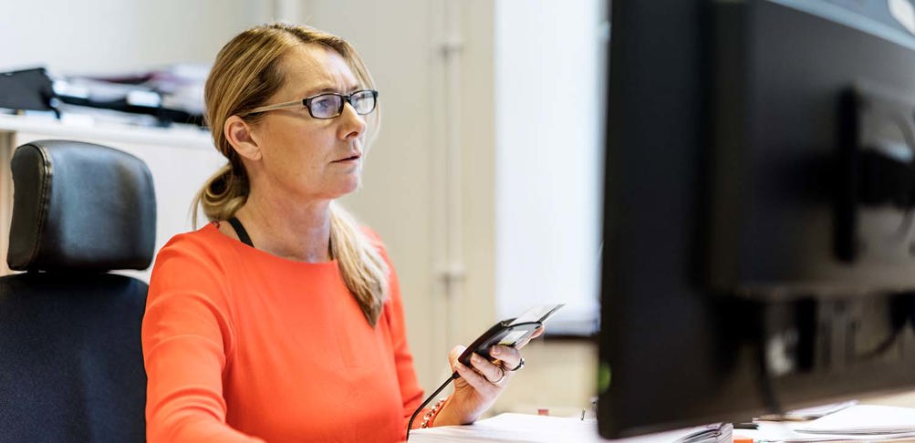 Kvinna vid dator signerar digitalt.