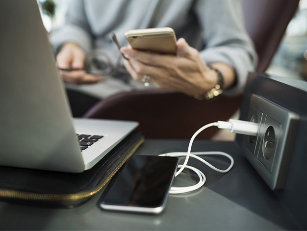 Närbild på bild som laddas vid ett el-uttag på ett tåg.