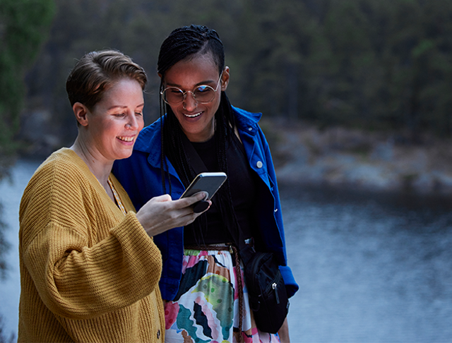 Två kvinnor tittar på en mobiltelefon.