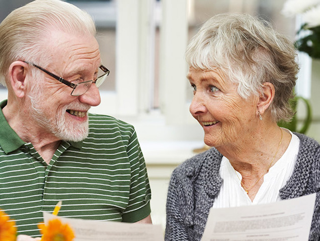 Ett äldre par tittar mot varandra och ler.